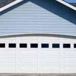 Arched garage door opening on new residence brightly lit up by the warm summer sun.